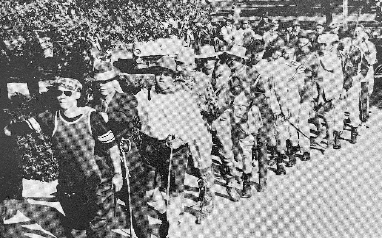 Black-and-white photo of Texas A&M students in costume marching in a line during Elephant Walk.