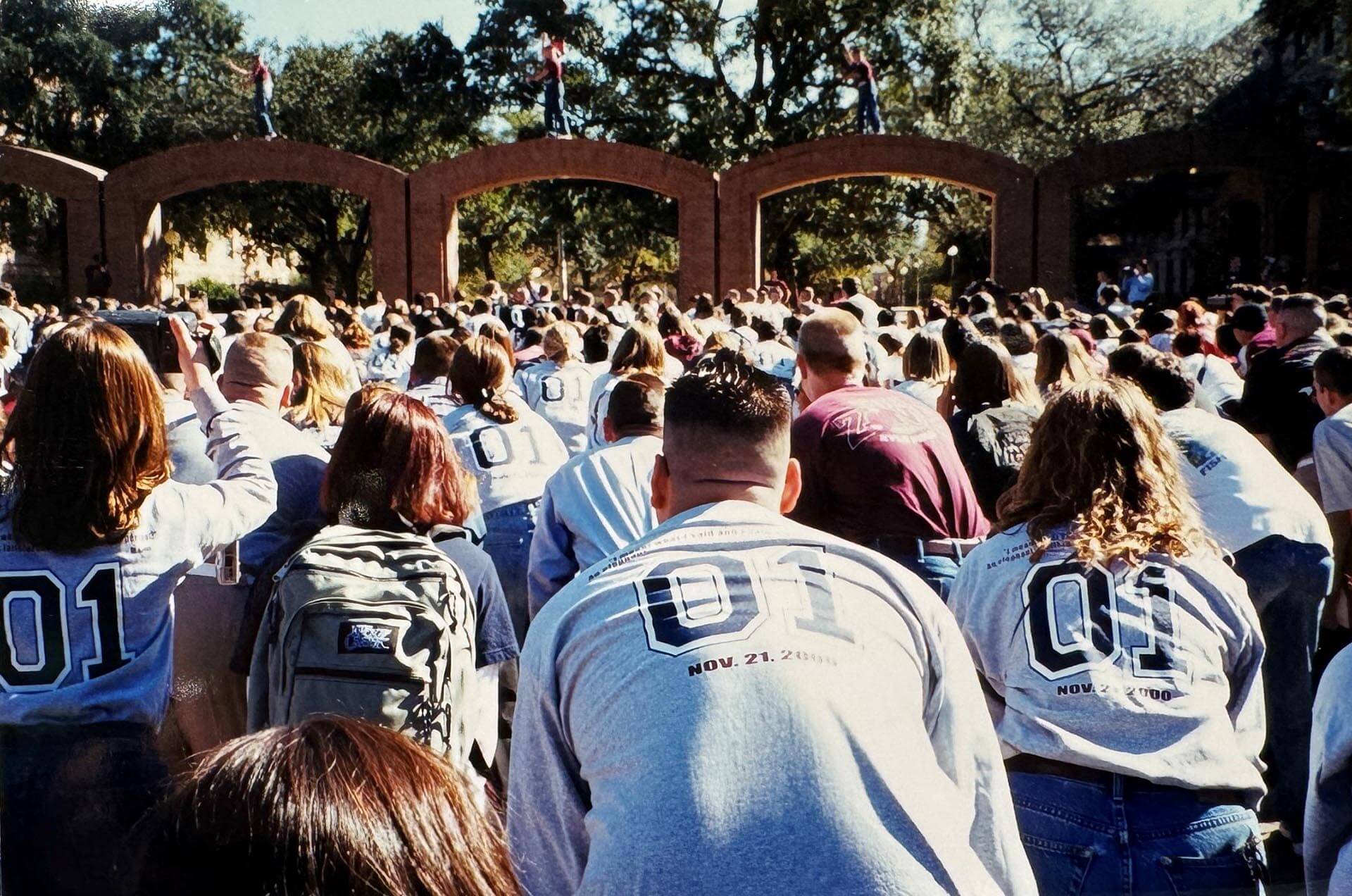 Color photo of Texas A&M students in Class of ’01 shirts gathered at the Quad arches during Elephant Walk.